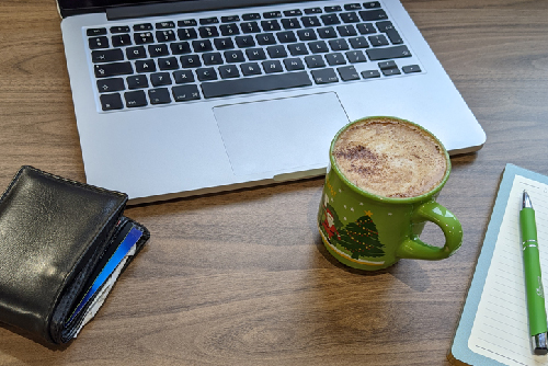 Table with a laptop, coffee in a Christmas cup and a wallet
