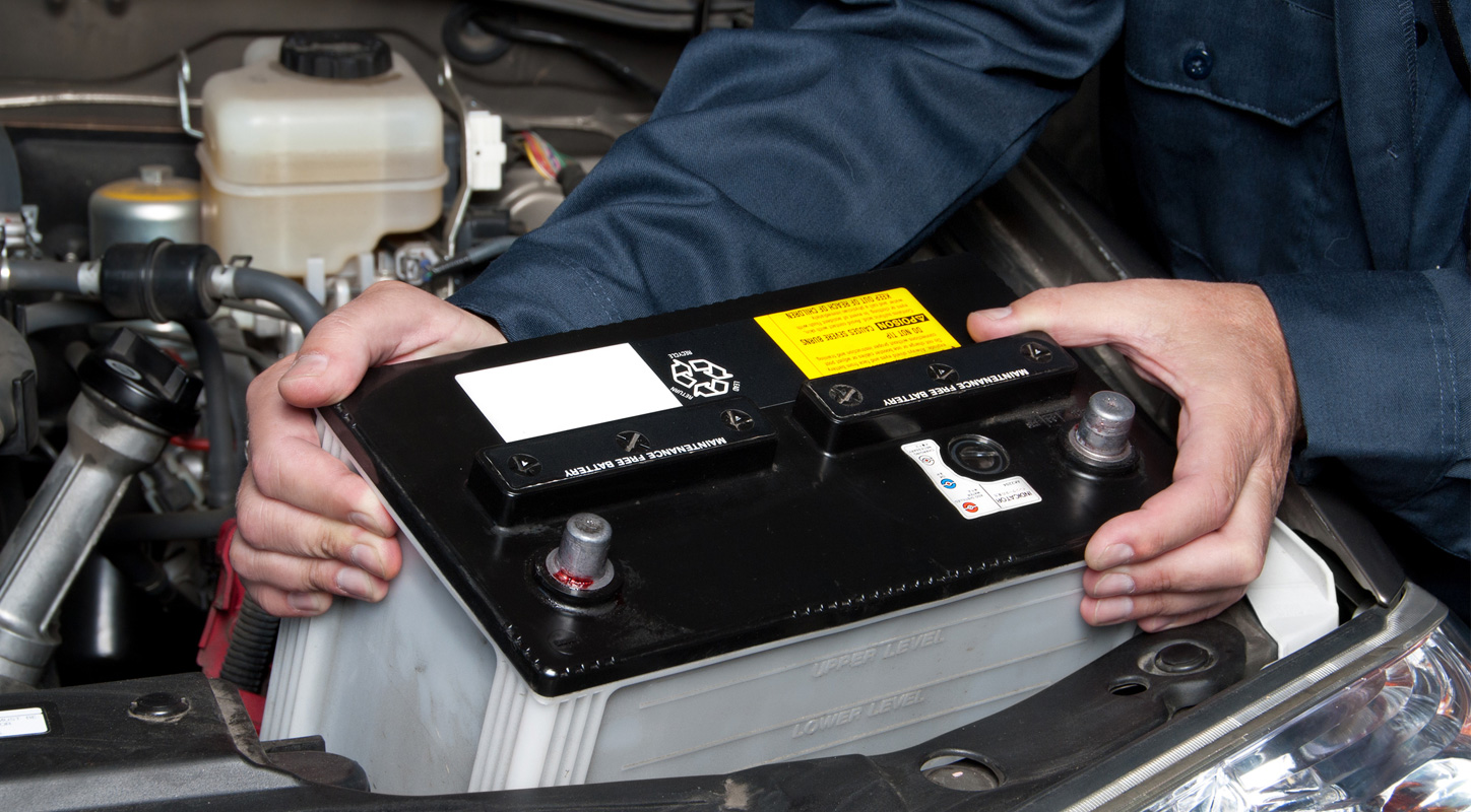 Close up photograph of a person removing a car battery
