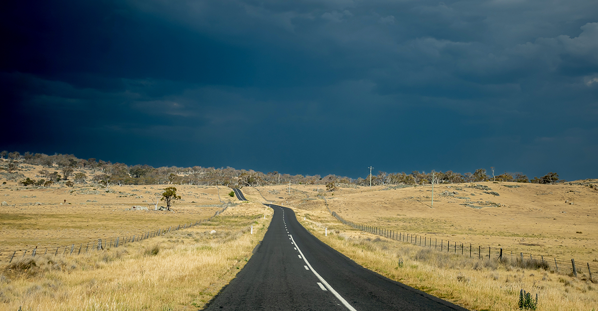 Dark storm clouds looming over rural road