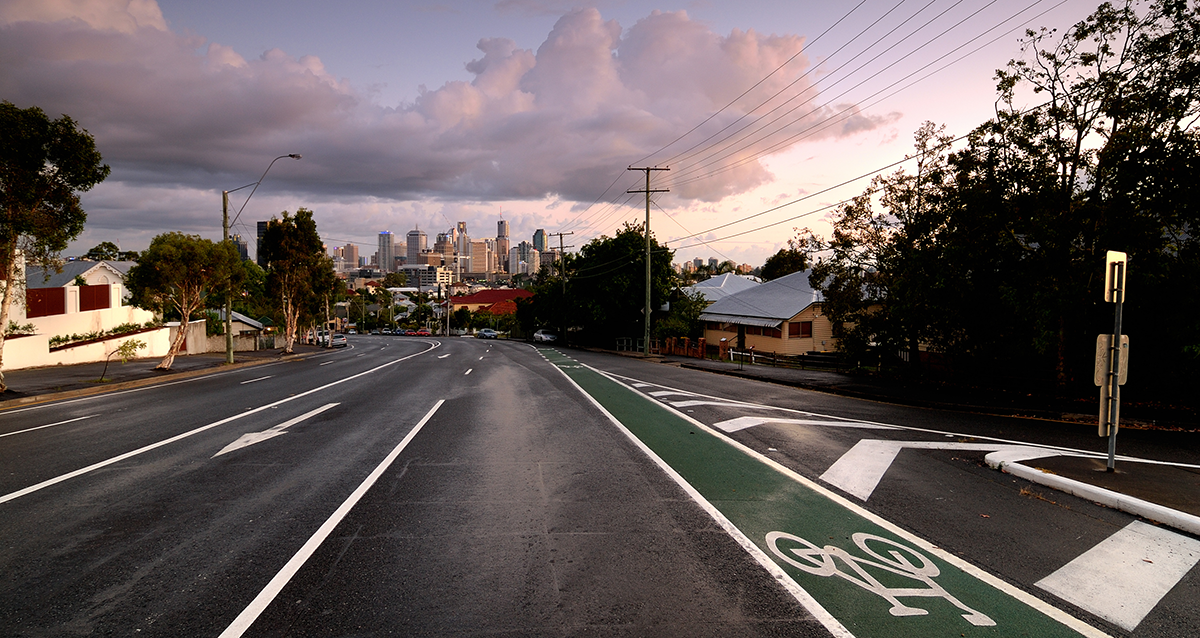 On road approaching storm clouds looming over cityscape